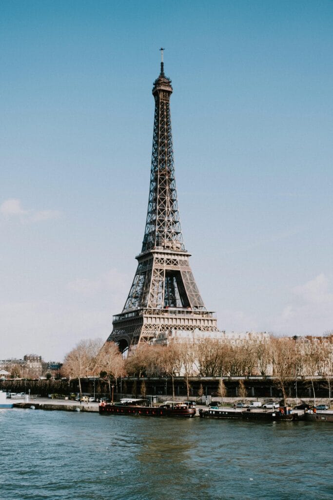 The Eiffel Tower standing tall with the Seine River in the foreground on a clear day in Paris, a must-visit stop in a Paris family itinerary