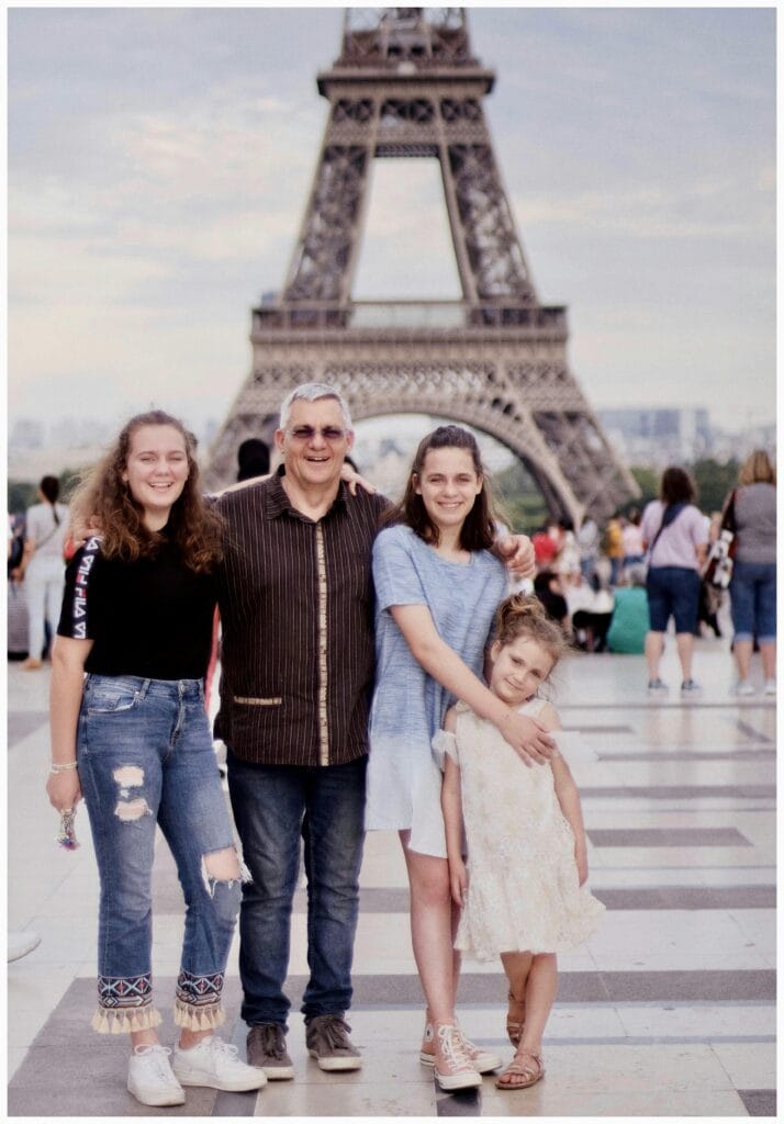 A happy family taking a photo near the Eiffel Tower in Paris, capturing a special travel moment together.