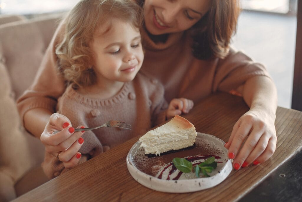 Mother and Daughter Enjoying Dessert at a Family Friendly Café in Paris Mother feeding daughter dessert at a cozy café — family friendly restaurants in Paris