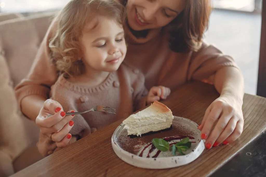 Mother and Daughter Enjoying Dessert at a Family Friendly Café in Paris Mother feeding daughter dessert at a cozy café — family friendly restaurants in Paris