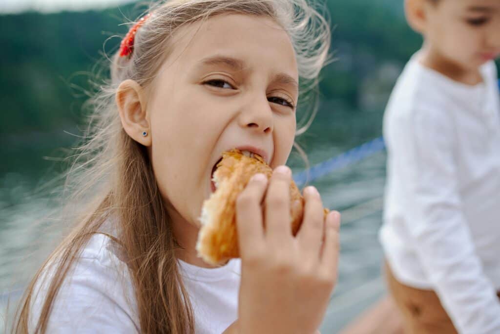 Goûter in Paris: Best Things to do in Paris with Tweens Happy girl eating a croissant during goûter time in Paris, best things to do in Paris with Tweens