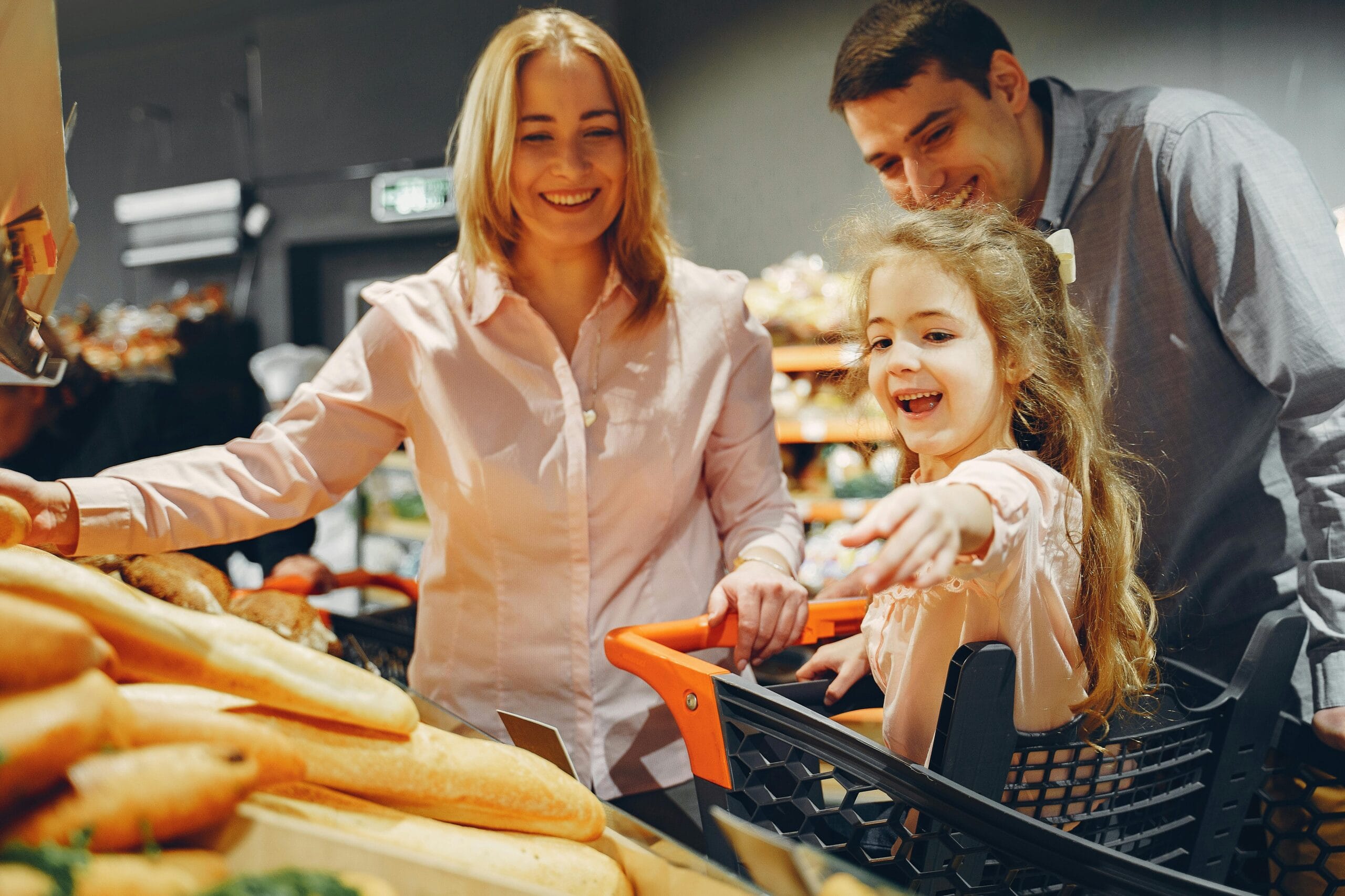A family shopping with their young daughter in a grocery store, finding essentials during a trip to Paris